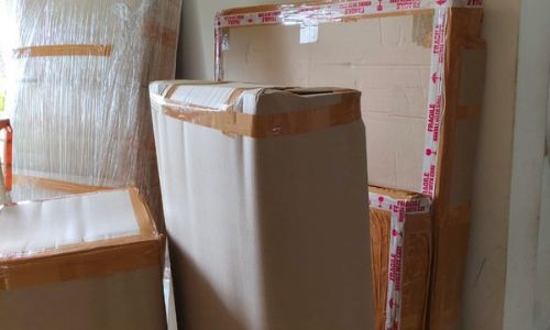 Euro Packers and Movers team preparing wooden wardrobes and home appliances with corner padding and fragile tape