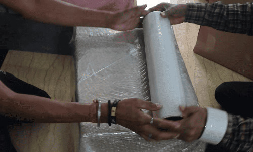 Euro Packers and Movers team securing parcel edges with thick layers of protective wrap inside a home