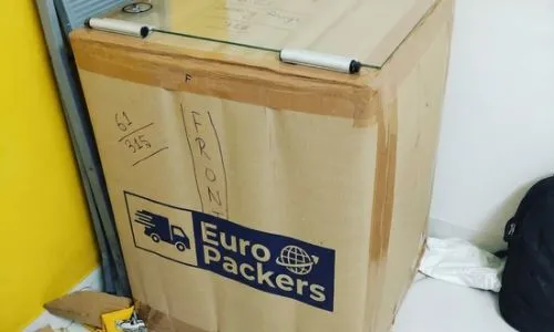 Cardboard boxes labeled with fragile tape and protective film packed by kolkata packers nad movers in a kitchen area.