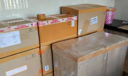 Cardboard boxes labeled with fragile tape and protective film packed by kolkata packers nad movers in a kitchen area.