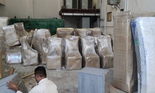 Shrink-wrapped office chairs and packed mattresses stored in the movers and packers warehouse