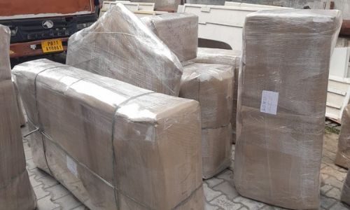 Packers and movers securing large household furniture with heavy-duty brown paper and thick plastic stretch film