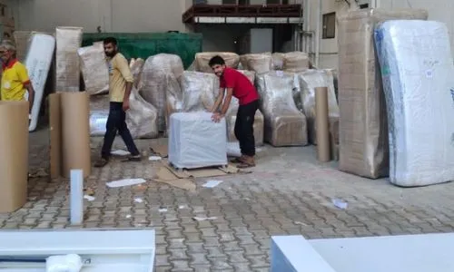 On-site moving team packing and moving wrapped furniture and household items, showcasing professional services from packers and movers in Kolkata.