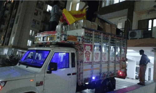 Household goods and large carton boxes being loaded onto a transport truck at night by packers and movers