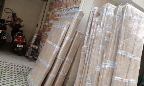 Wooden boards and furniture panels wrapped in brown sheets by movers and packers during a home shifting job.
